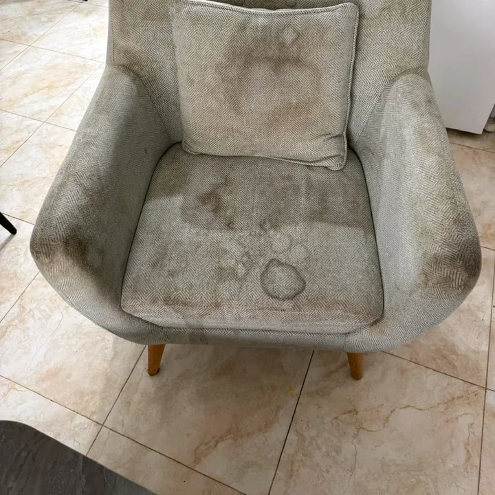 כורסה מרופדת עם כתמים לפני ניקוי